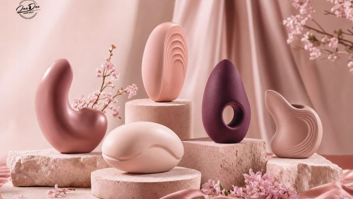 care-este-cel-mai-bun-vibrator-ce-arata-sase-luni-de-vanzari-pe-tipuri-si-cum-alegi-pentru-tine.jpg Forme abstracte în tonuri de roz și prună pe postamente de piatră, cu flori de cireș, cu logo OneDee